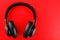 Wireless black headphones on a red background. View from above. In-ear headphones for playing games and listening to music tracks