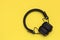 Wireless black headphones on yellow background. Trendy vintage accessories in creative retro design. Music hipster concept in