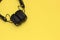 Wireless black headphones on yellow background. Trendy vintage accessories in creative retro design. Music hipster concept in
