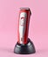 Wireless clipper stands at the charging station isolated on a pink background.