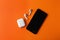 Wireless earphones, mobile phone and charging case on orange background, flat lay. Space