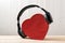 Wireless full-size headphones wearing a red heart-shaped box. Love music concept. Front view