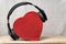 Wireless full-size headphones wearing a red heart-shaped box. Love music concept. Front view