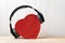 Wireless full-size headphones wearing a red heart-shaped box. Love music concept. Front view