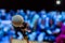 Wireless microphone on the stand. Blurred background. People in the audience. Show on stage in the theater or concert hall