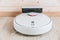 Wireless robot vacuum cleaner return to charging at dock in clean wooden floor