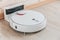 Wireless robot vacuum cleaner return to charging at dock in clean wooden floor