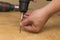 Wireless screwdriver in the hands of a man, on a wooden background, the theme of repair work