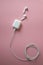 Wireless white headphones on pink background. Airpods. white wireless headphones with a charger connected to a power cable coiled