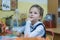 A wise schoolgirl of primary classes sits at a desk and listens to a lesson. Day of knowledge