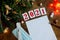 wish sheet on a wooden background with the numbers 2021, a blank sheet of paper, mask, syringe, covid-19 vaccine, led is a garland