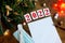 Wish sheet on a wooden background with the numbers 2021, a blank sheet of paper, mask, syringe, covid-19 vaccine, led is a garland