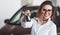 Wishes you good ride. Friendly female manager stands against red car in automobile salon