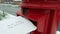 Wishlist letter to Santa being posted in a mailbox on a snowy Christmas day