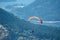 Witness a thrilling sight as a person gracefully paraglides through the sky over majestic mountain peaks, with a serene