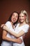 Wo pretty diverse girls happy posing together: blond and brunette on brown background, lifestyle people concept