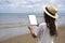 A woamn holding a black tablet pc with blank desktop screen by the sea