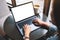 A woamn using and typing on laptop with blank white desktop screen with coffee cup on the table