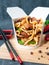 Wok box with noodles oyster sauce and coconut milk, beef, wood mushroom, green beans..The wok box is cut. Standing on a mat next