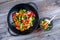 wok with vegetables, bowl of rice and chopsticks on wooden groun