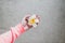 Woma`s hand holding white and yellow frangipani flower with concrete background