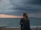 A womam is Sitting on a beach in Puerto Rico, watching the sunset and the arrival of a storm over the Caribbean Sea. Rincon,