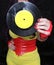 Woman in 1980s yellow clothing holding 45rpm record. Record label painted with yellow poster paint