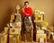 Woman among 2 piles of golden gifts in front of plain wall