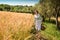 Woman in 40s clothes walks in the Italian countryside, next to a wheat field, carrying a basket of cherries