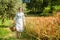 Woman in 40s clothes walks in the Italian countryside, next to a wheat field, carrying a basket of cherries