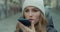 Woman activates smartphone digital virtual app voice assistant recording audio messages at outdoor. Young girl in hat