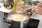 Woman adding butter into saucepan with boiled rice in kitchen