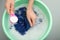 Woman adding detergent into basin with color clothes