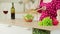 Woman adding fresh cucumber slices in glass bowl with salad. Vitamins, dietary and sports nutrition. Vegetarian food.