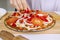 Woman adding fresh paprika for raw pizza