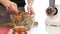 Woman adding honey to a nut butter and mixing ingredients in bowl