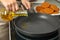 Woman adding oil on frying pan, closeup. Cooking breaded cutlets