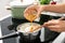 Woman adding oil to boiled rice in saucepan, closeup