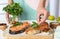 Woman adding parsley to cooked red fish on wooden table, closeup