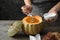 Woman adding sour cream into pumpkin bowl with tasty cream soup at wooden table