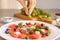 Woman adding sunflower seeds to sweet salad with watermelon and feta on plate, closeup