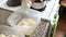 A woman adds cottage cheese to a container with melted butter, vanilla and powdered sugar. Ingredients for dessert.