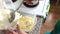 A woman adds cottage cheese to a container with melted butter, vanilla and powdered sugar. Ingredients for dessert.