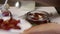 A woman adds garlic and dried tomatoes to a jar. It has a branch of rosemary, garlic and spices. Poured with olive oil