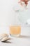 Woman adds psyllium fiber to glass of water on a white background.