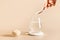 Woman adds psyllium fiber to glass of water on a white background.