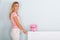 Woman Adjusting Thermostat With Piggy Bank On Radiator