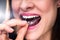 Woman Adjusting Transparent Aligners In Her Teeth