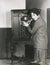 Woman adjusting volume on 1920s radio