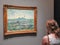 A woman admires a painting by Van Gogh